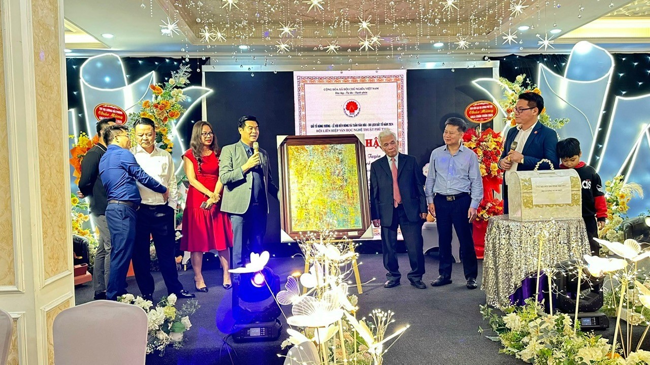 Anh Lương Minh Thắng (đứng bên phải bức tranh) - người trúng đấu giá trị giá 65 triệu đồng